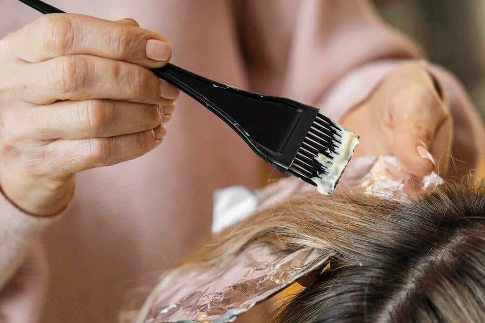 Hair coloring process with a brush applying dye to hair over foil.