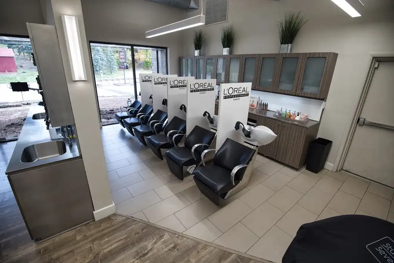 Modern salon with sleek hair-washing stations and large windows.